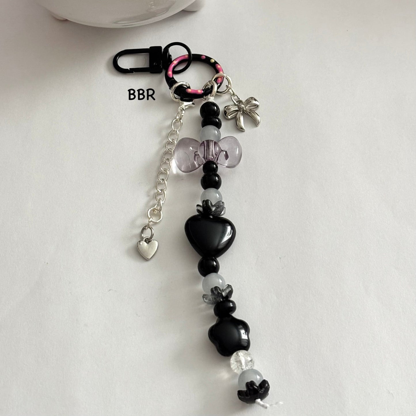 Handmade black beaded bag charm with a beautiful translucent bow, a sliver bow and heart charm on a black swivel snap hook for easy attachment.
