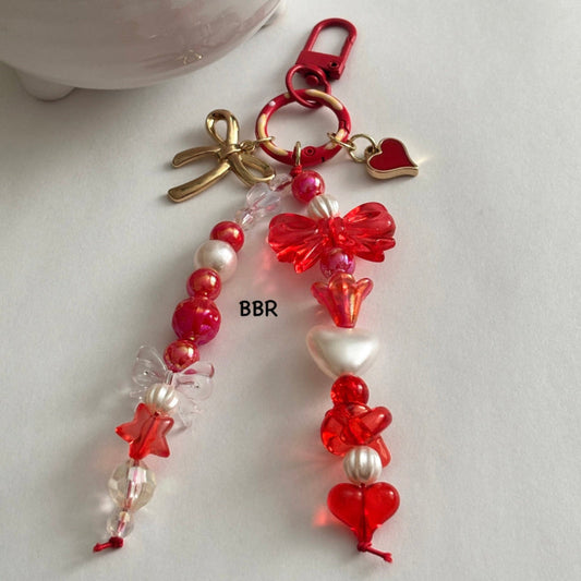 Handmade red beaded bag charm with a beautiful transparent bow bead, a gold bow and red heart charm on a red swivel snap hook for easy attachment.
