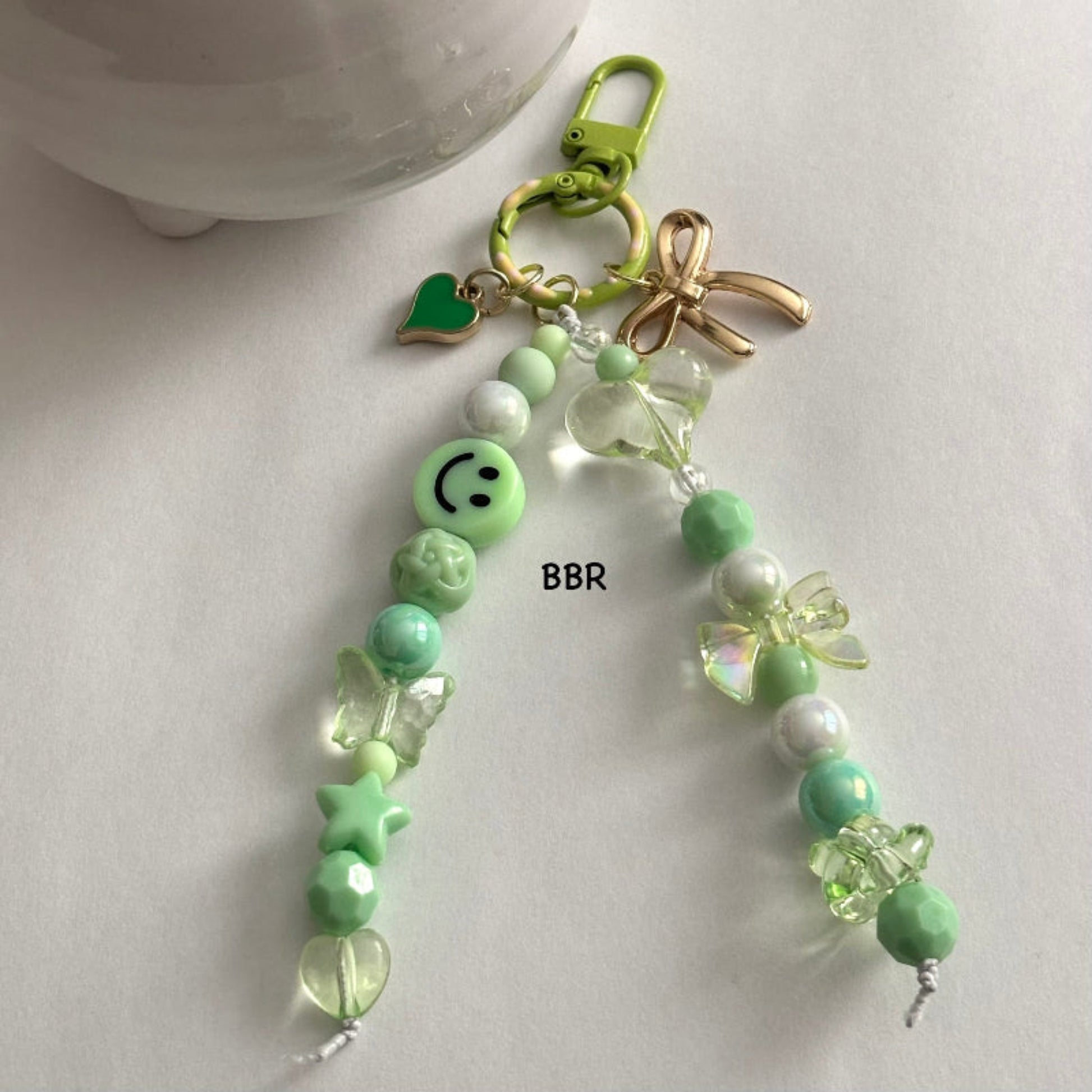Handmade green beaded bag charm with a beautiful translucent heart & bow bead, a gold bow and green heart charm on a green swivel snap hook for easy attachment.