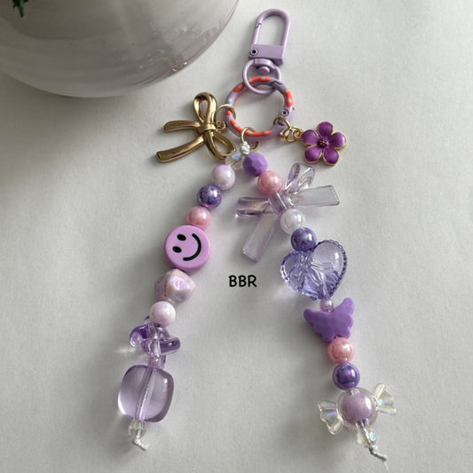 Handmade purple beaded bag charm with a beautiful translucent purple bow & heart bead, a gold bow and purple flower charm on a purple swivel snap hook for easy attachment.
