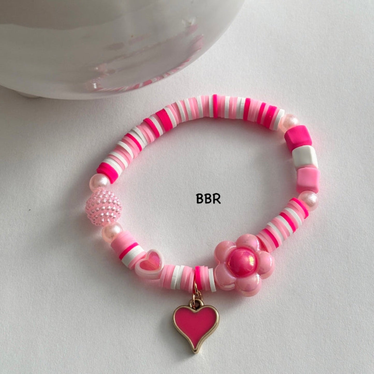 Handmade pink clay bead bracelet with a pink heart charm.
