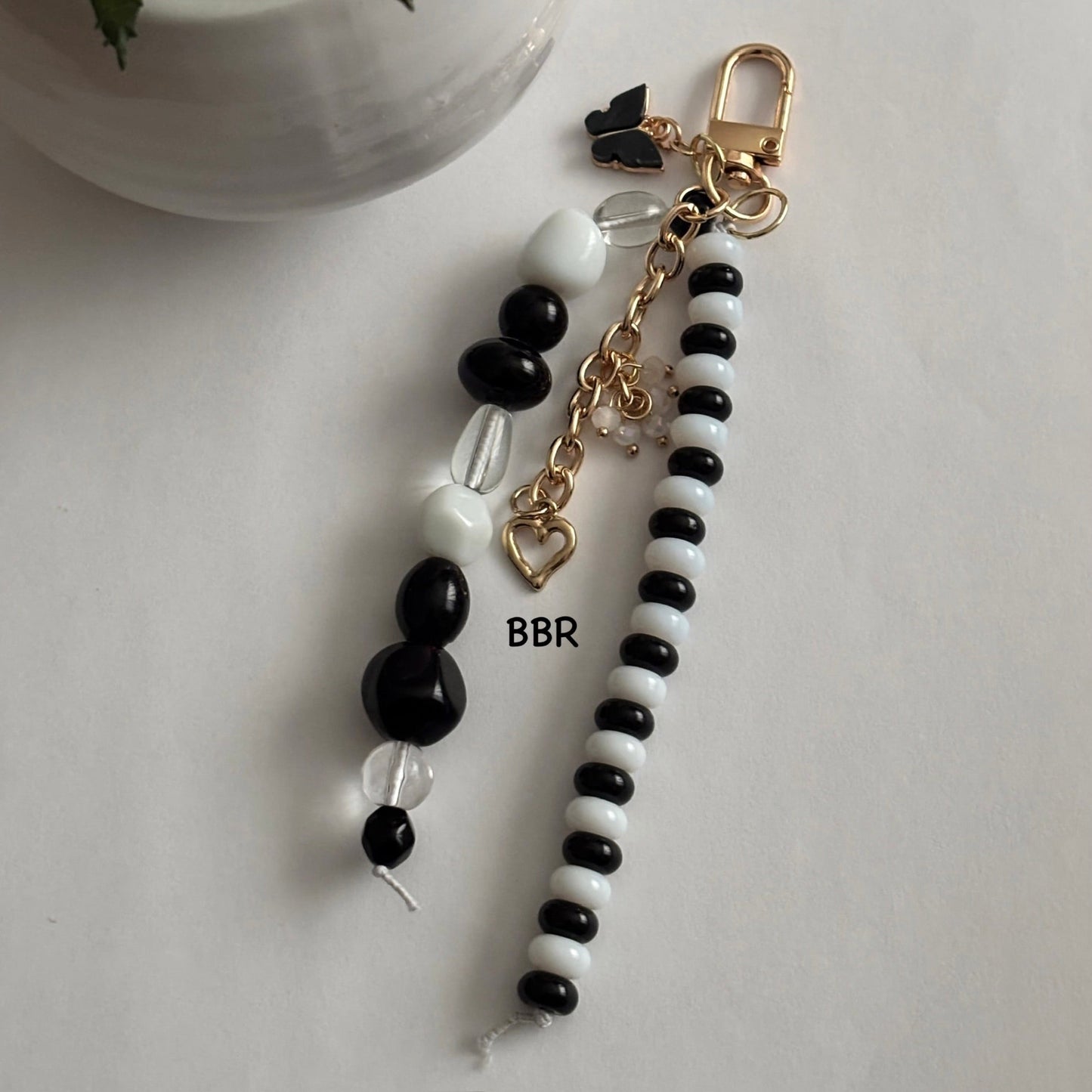 Handmade black and white beaded bag charm with a gold link with charms.