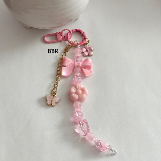 Handmade pink beaded bag charm with a beautiful pink pearlescent bow, a pink flower, and butterfly charm on a pink swivel snap hook for easy attachment. 
